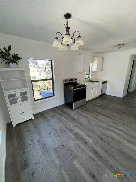 kitchen featuring stainless steel appliances, white cabinetry, sink, dark hardwood / wood-style floors, and decorative light fixtures