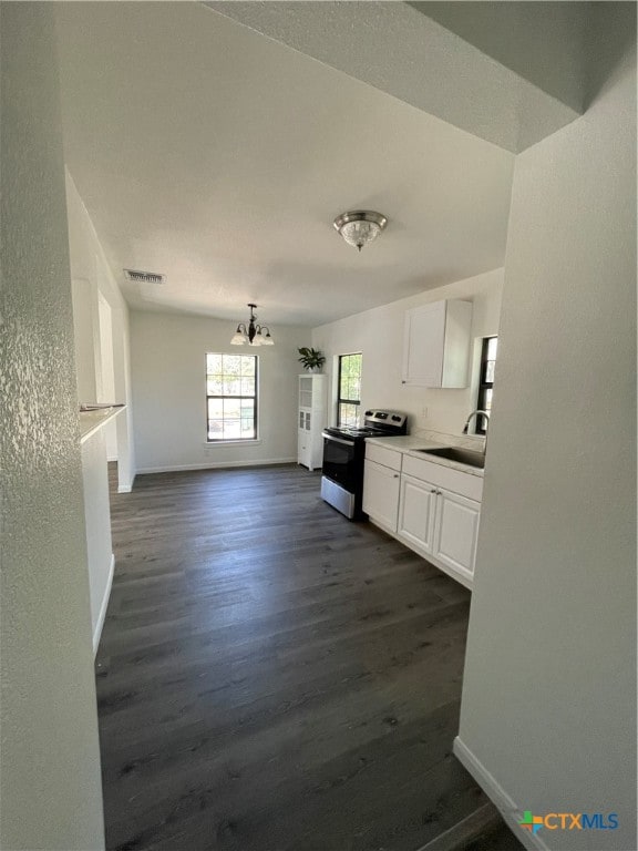 kitchen featuring stainless steel range with electric cooktop, white cabinetry, a notable chandelier, dark hardwood / wood-style floors, and sink