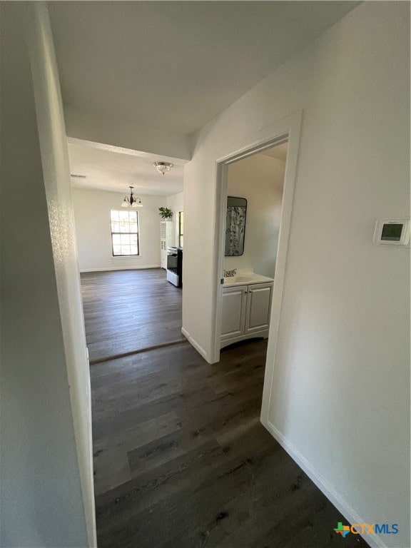 hallway with an inviting chandelier and dark hardwood / wood-style floors