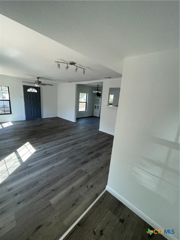 unfurnished living room featuring a textured ceiling, dark hardwood / wood-style floors, and ceiling fan