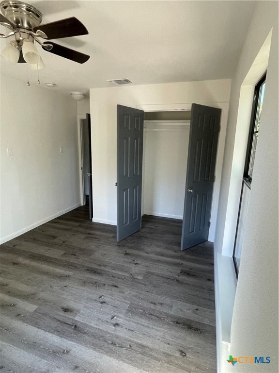 unfurnished bedroom featuring dark wood-type flooring, a closet, and ceiling fan