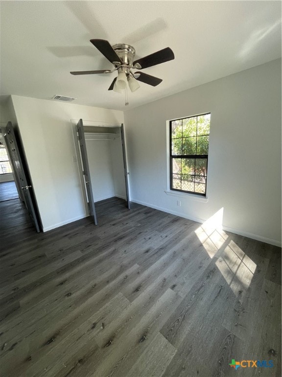 unfurnished bedroom featuring dark wood-type flooring, a closet, and ceiling fan