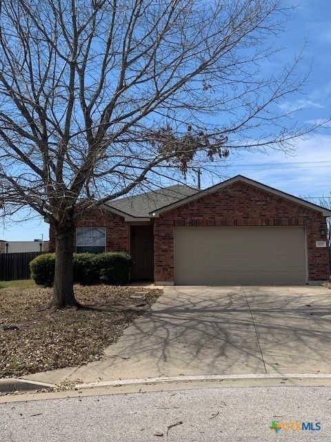 view of front of property with concrete driveway, an attached garage, fence, and brick siding