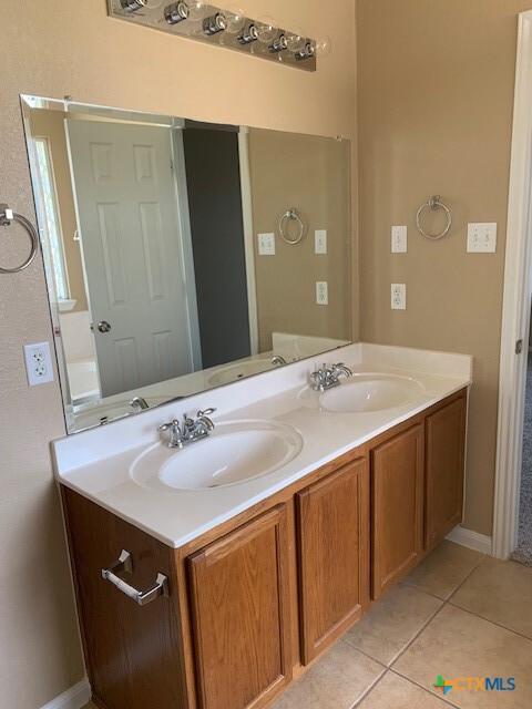 bathroom featuring tile patterned flooring, double vanity, and a sink