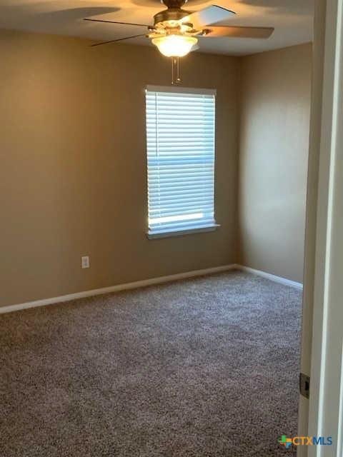 unfurnished room featuring a ceiling fan, baseboards, and carpet floors