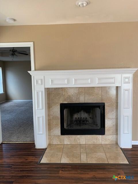 interior details with a tiled fireplace and wood finished floors