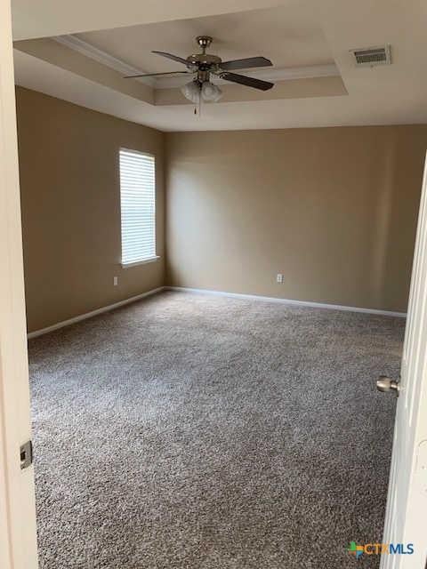 unfurnished room featuring visible vents, baseboards, a tray ceiling, and ornamental molding