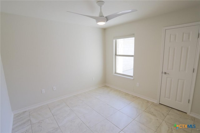 spare room with baseboards and a ceiling fan