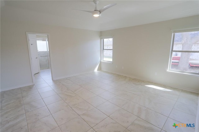 empty room with light tile patterned floors, ceiling fan, and baseboards