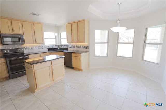 kitchen with a tray ceiling, stainless steel appliances, dark countertops, backsplash, and light brown cabinetry