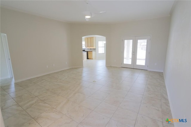 unfurnished room with ornamental molding, arched walkways, french doors, and baseboards