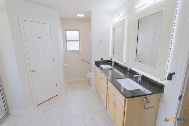 bathroom featuring double vanity, a sink, toilet, and baseboards