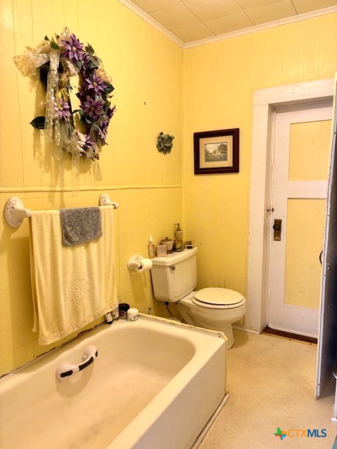 bathroom with a bath, toilet, and crown molding