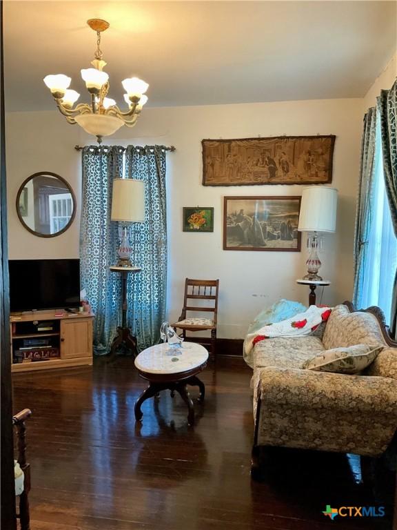 sitting room with baseboards, a notable chandelier, and wood finished floors