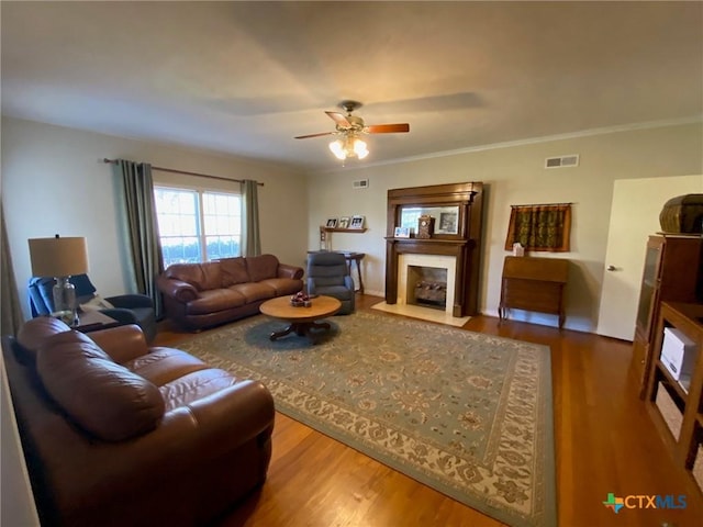 living room featuring hardwood / wood-style flooring, ceiling fan, and ornamental molding