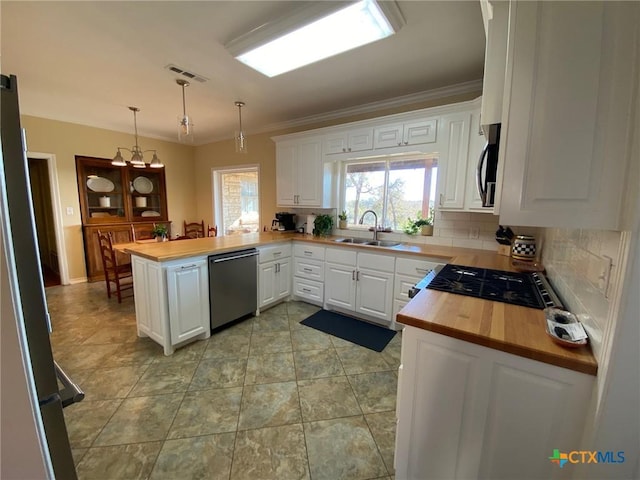 kitchen with kitchen peninsula, decorative light fixtures, and white cabinetry