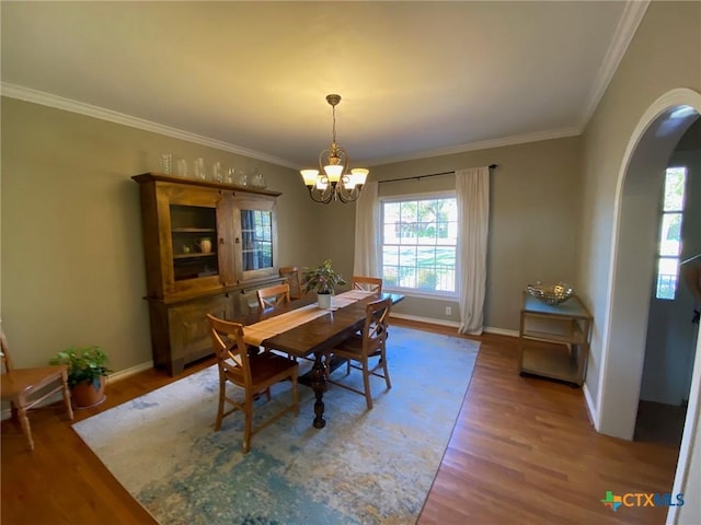 dining space featuring wood-type flooring, crown molding, and a notable chandelier