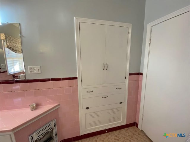 bathroom featuring heating unit and tile walls