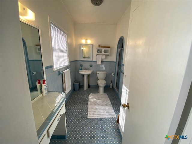 bathroom with toilet, sink, and tile walls