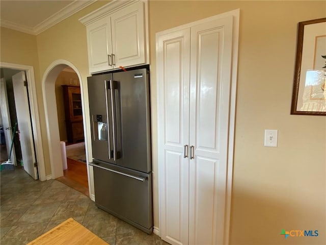 kitchen with white cabinetry, ornamental molding, stainless steel refrigerator with ice dispenser, and light tile patterned floors