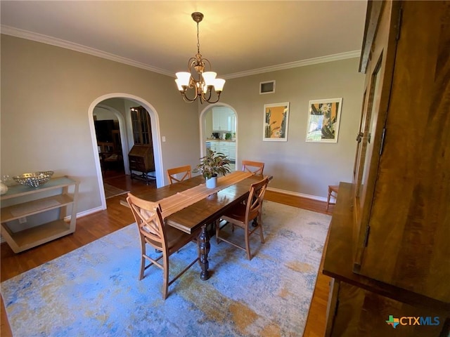 dining room with ornamental molding, a chandelier, and hardwood / wood-style flooring