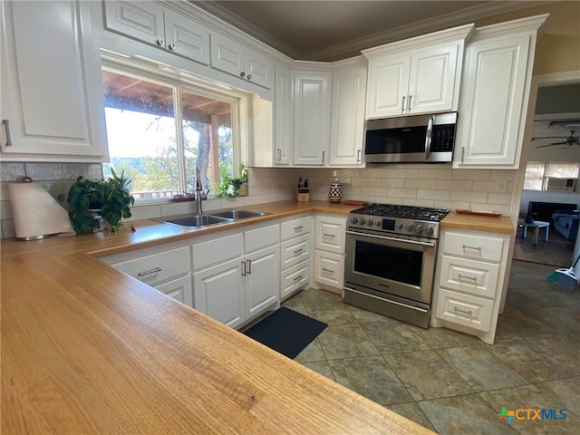 kitchen with white cabinets, stainless steel appliances, tasteful backsplash, and wood counters