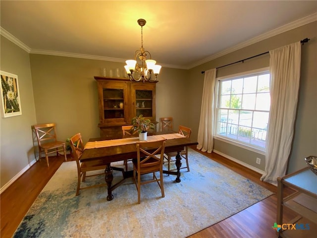 dining area featuring hardwood / wood-style floors, ornamental molding, and a notable chandelier