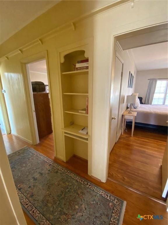 hallway featuring hardwood / wood-style flooring and built in features