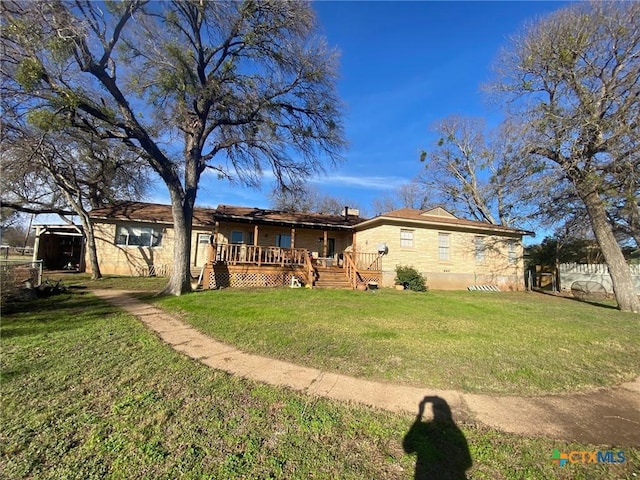 rear view of house featuring a lawn and a wooden deck