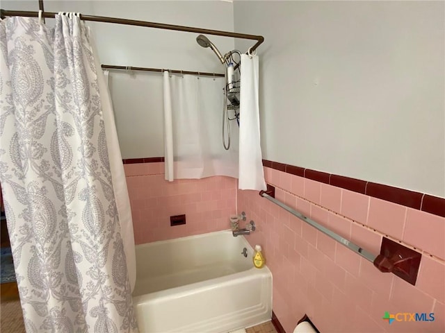 bathroom featuring shower / bathtub combination with curtain and tile walls