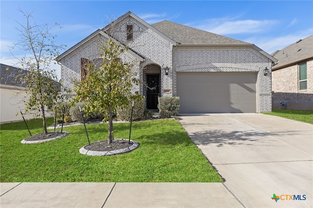 french country style house with a garage, a front yard, brick siding, and driveway