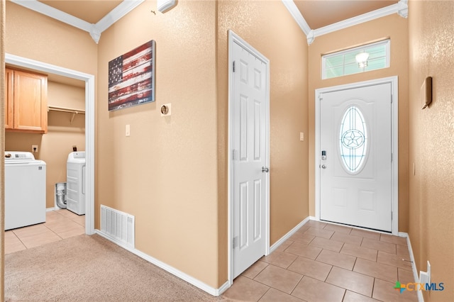 tiled foyer entrance with crown molding and independent washer and dryer