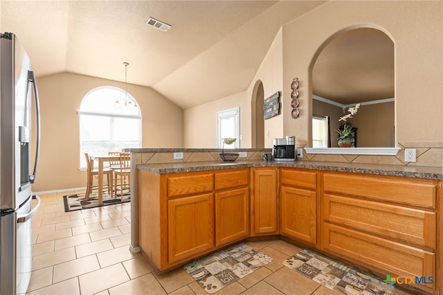 kitchen featuring kitchen peninsula, stainless steel fridge, light tile patterned floors, and vaulted ceiling