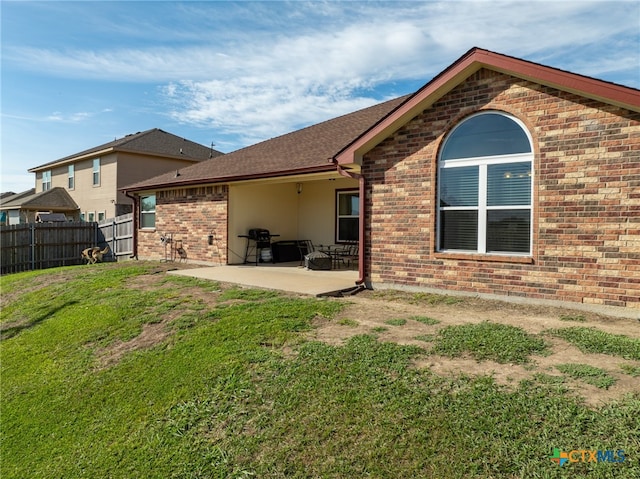 rear view of house featuring a lawn and a patio