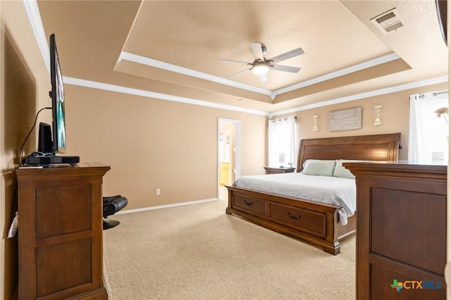 bedroom featuring ceiling fan, light colored carpet, connected bathroom, and a tray ceiling