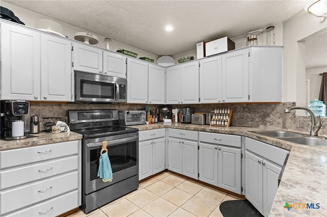 kitchen with a sink, stainless steel appliances, decorative backsplash, and light tile patterned floors