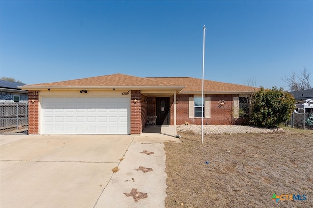 ranch-style home featuring driveway, fence, an attached garage, a shingled roof, and brick siding