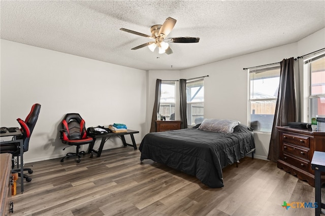 bedroom with wood finished floors, baseboards, and a textured ceiling