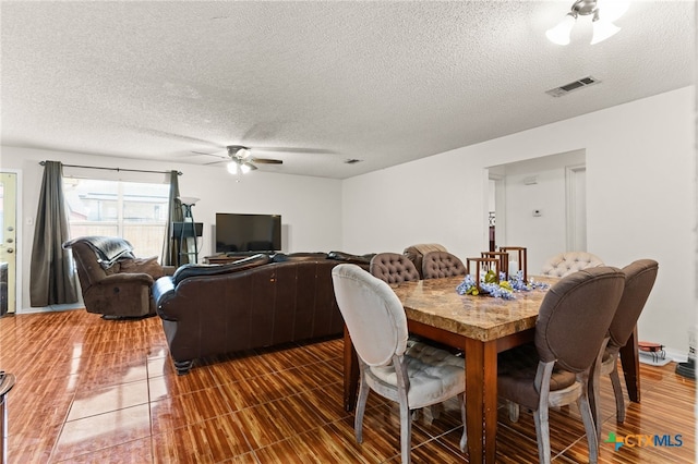 dining space with visible vents, a textured ceiling, and a ceiling fan