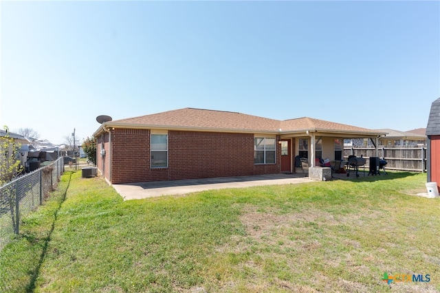 rear view of property featuring a fenced backyard, a lawn, and a patio