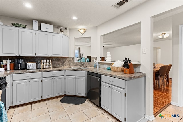 kitchen featuring visible vents, dishwasher, light tile patterned floors, gray cabinets, and a sink