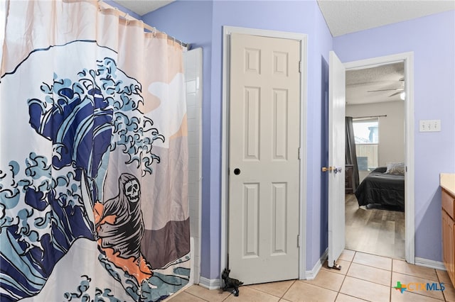 ensuite bathroom with tile patterned floors, a textured ceiling, ensuite bath, baseboards, and vanity