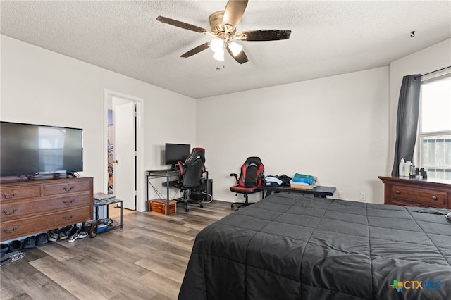 bedroom with ceiling fan, a textured ceiling, and wood finished floors