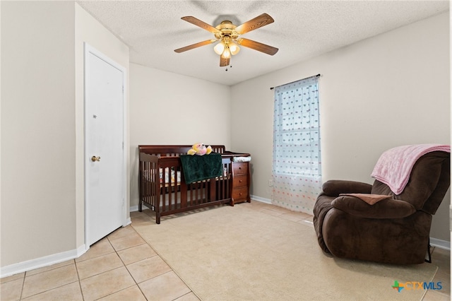 bedroom featuring baseboards, ceiling fan, light colored carpet, light tile patterned floors, and a textured ceiling