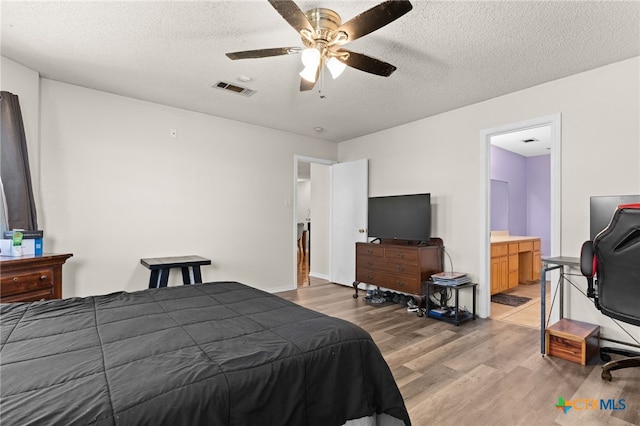 bedroom with visible vents, ensuite bathroom, a textured ceiling, light wood-style floors, and ceiling fan