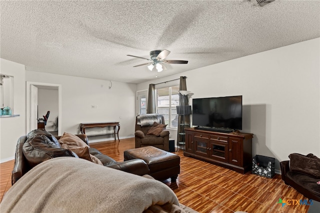 living area featuring visible vents, baseboards, a textured ceiling, and ceiling fan