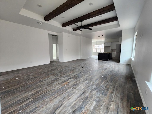 unfurnished living room with beam ceiling, ceiling fan, and dark hardwood / wood-style flooring