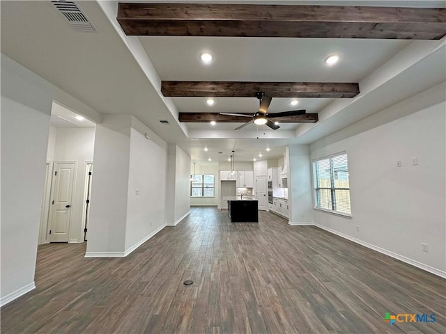 unfurnished living room with dark wood-style floors, beam ceiling, visible vents, and baseboards