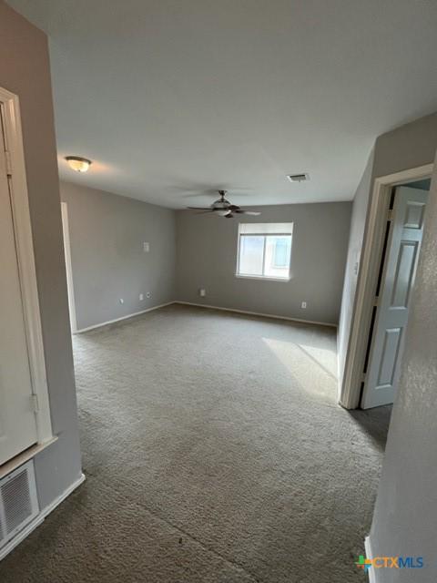 empty room featuring baseboards, carpet, a ceiling fan, and visible vents