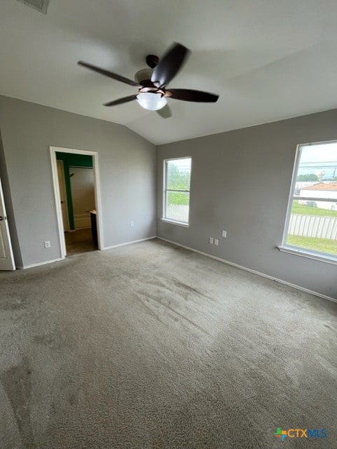 carpeted spare room featuring baseboards, visible vents, ceiling fan, and lofted ceiling